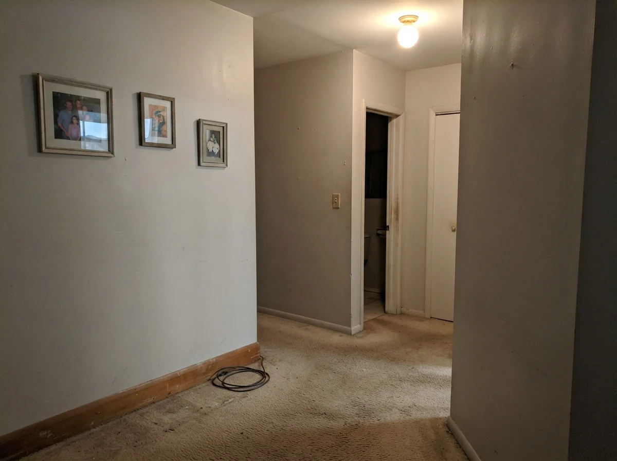 Dim windowless hallway corner showing Benjamin Moore Calm looking muddy and flat.