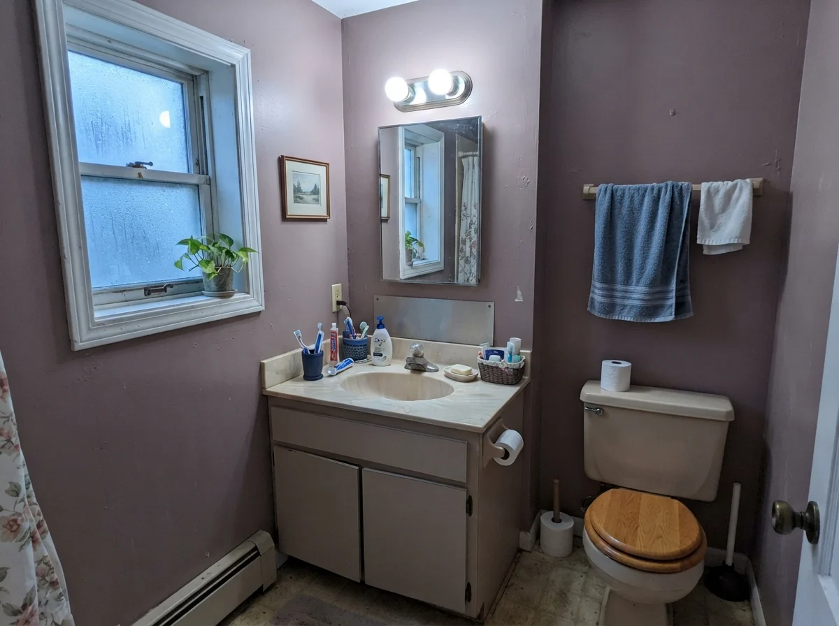 Modest bathroom with cool-cast painted walls, small window, and older beige vanity