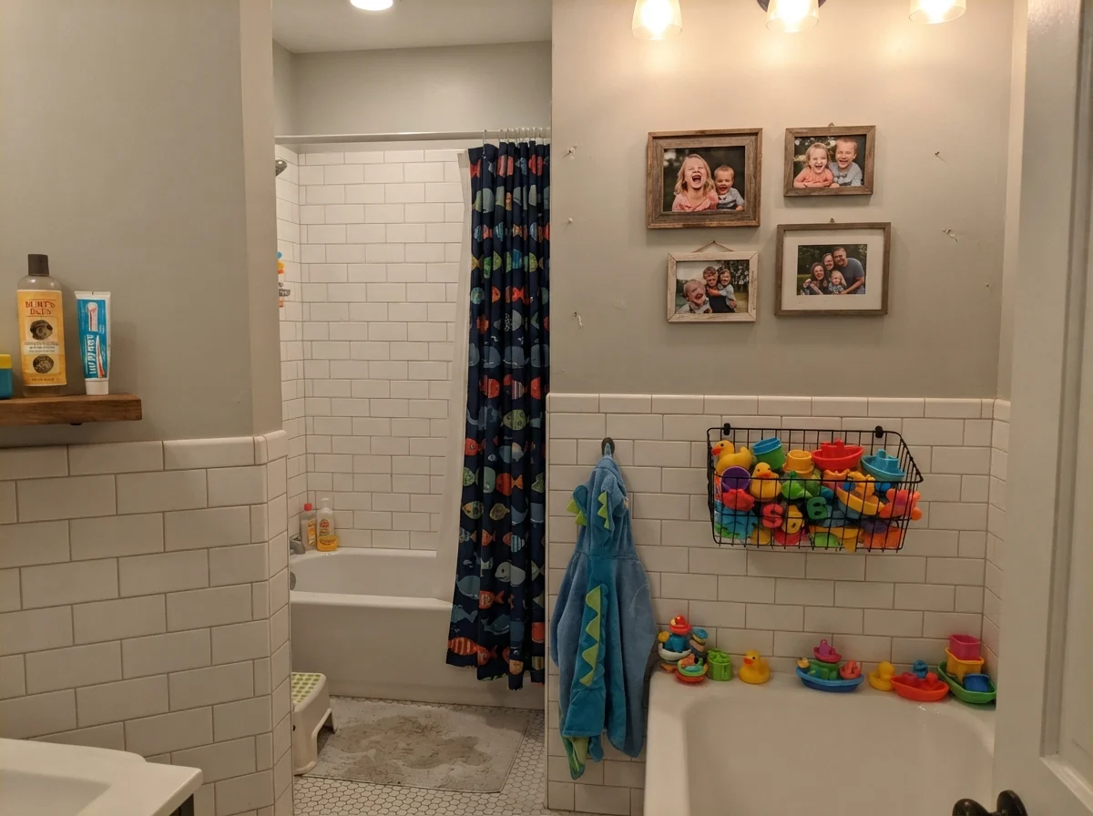 Kids' bathroom with subway tile wainscot, Gray Owl upper walls, and colorful bath toys.
