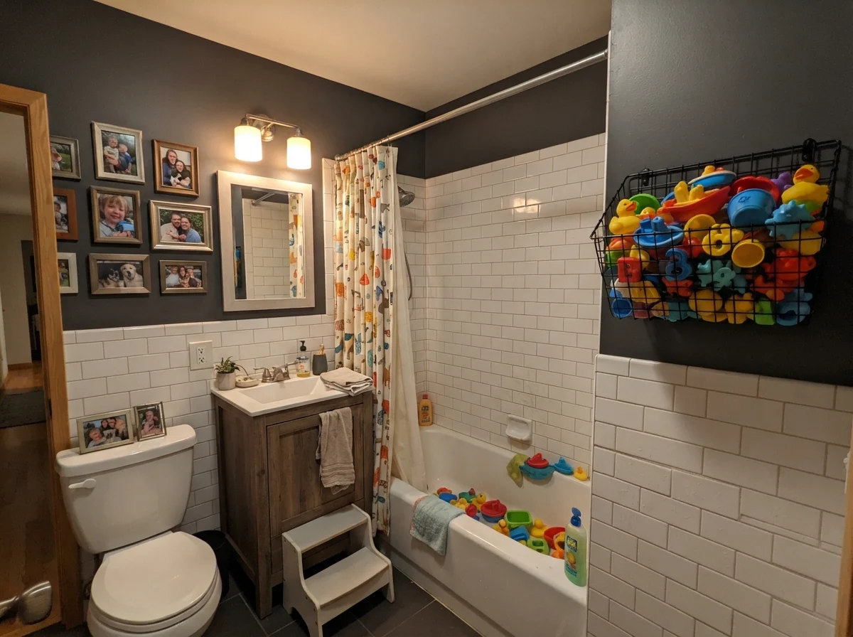 Kids bathroom with painted upper walls, white subway tile, and colorful bath toys.