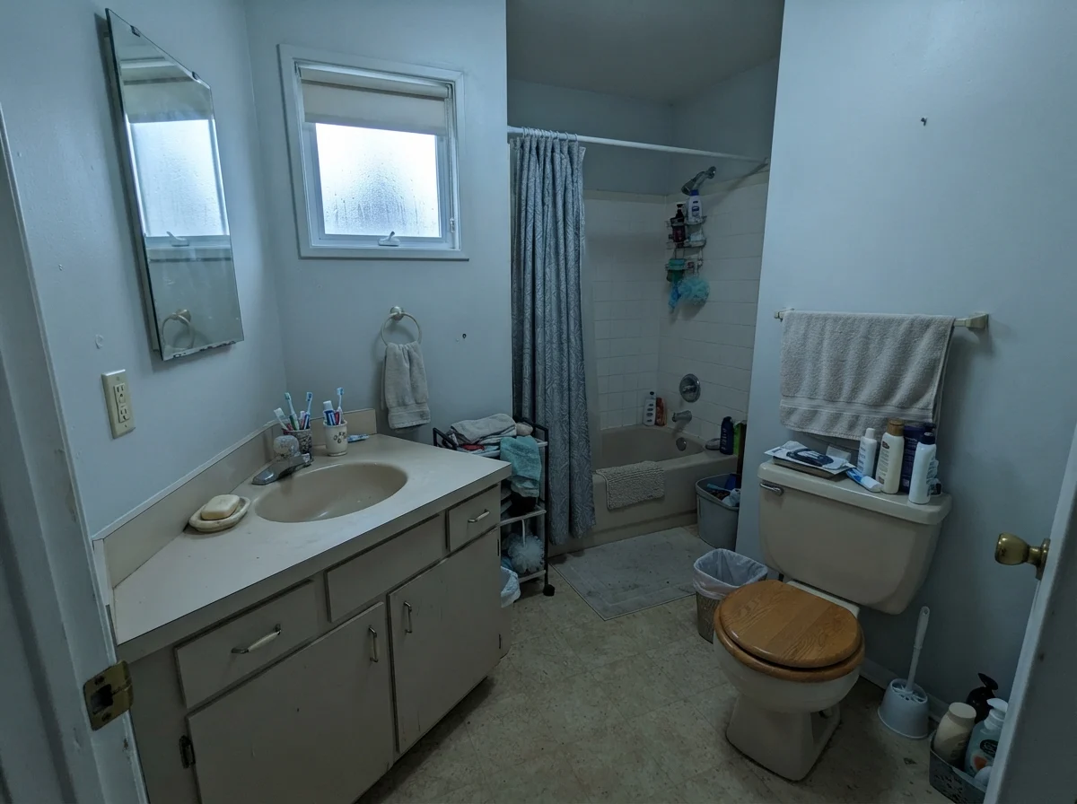 Modest dated bathroom with older beige vanity and painted walls picking up a cool cast.