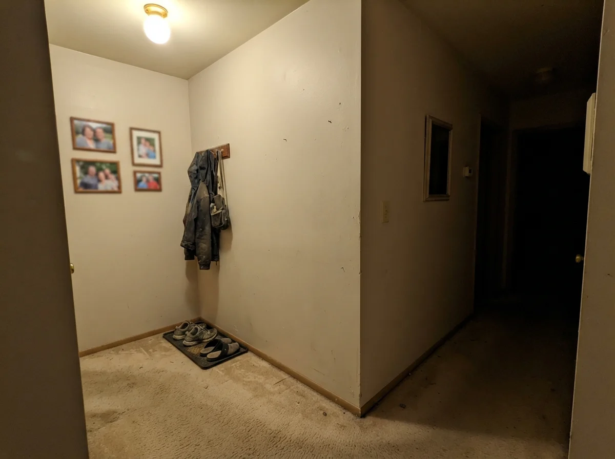Dim windowless hallway corner showing Natural Linen reading muddy and flat under a single bulb